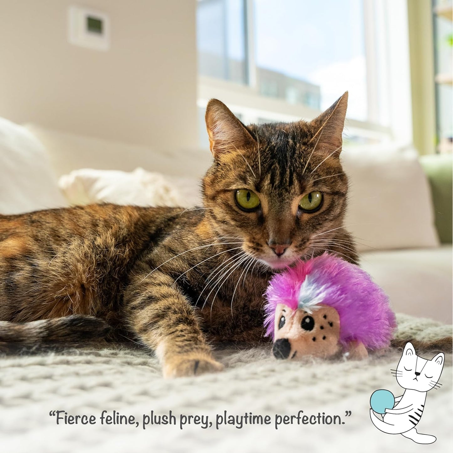 Purple and pink hedgehog catnip plush held by a tabby cat on a couch