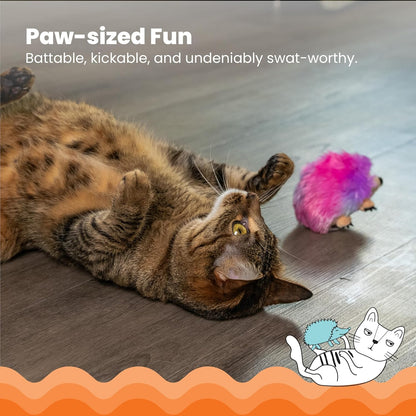 Purple and pink hedgehog catnip plush near a tabby cat on hardwood floor