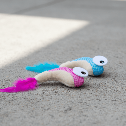 Two plush catnip shrimp toys on floor: pink and blue with feather tails
