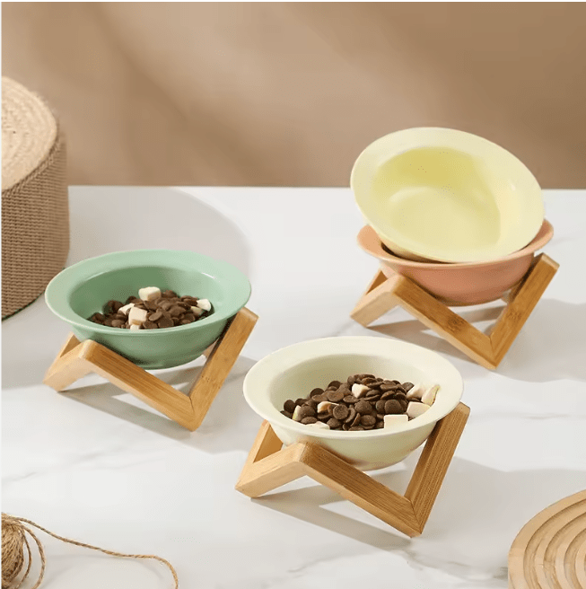 Elevated ceramic cat bowls with bamboo stands in green, cream, and yellow
