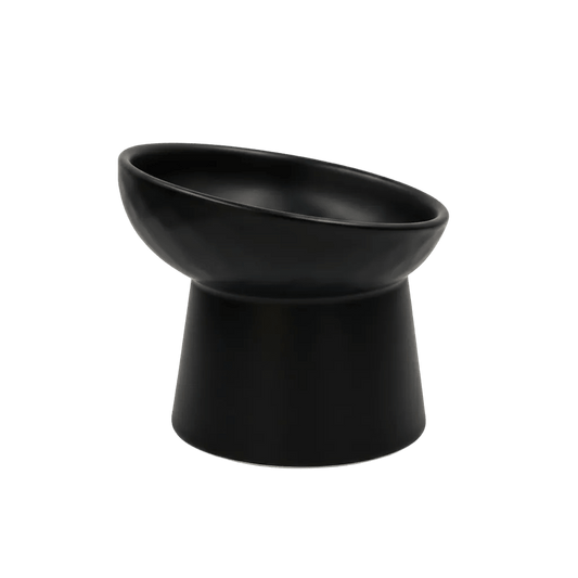 Black tilted ceramic cat bowl, side view; shallow bowl with wide rim on pedestal base.
