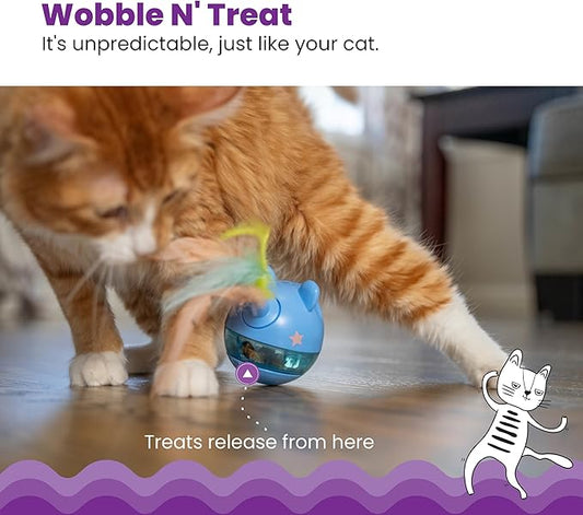 Cat playing with blue treat tumbler toy with feather wand; treats-release opening visible