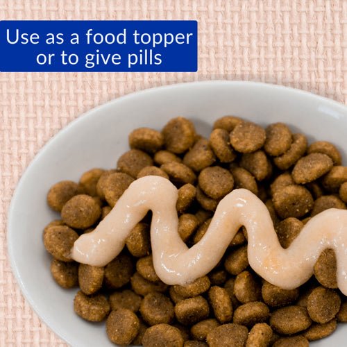Cat treat pellets topped with creamy chicken paste in white bowl