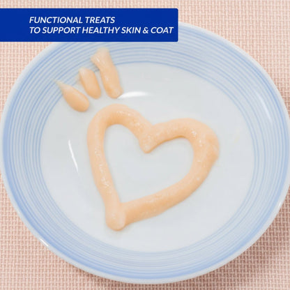 Creamy lickable cat treat paste in blue-rim bowl, pale peach