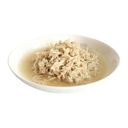 Wet cat food in broth with shredded meat served in a white oval dish
