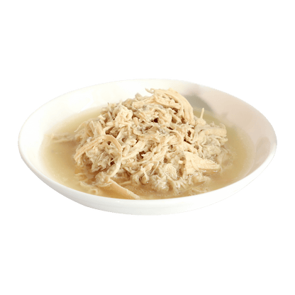 Wet cat food with shredded meat in broth served in a white oval dish
