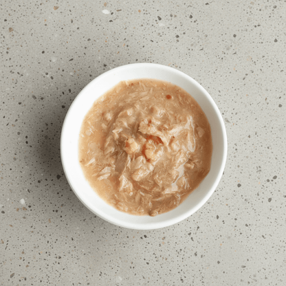 Wet cat food in white bowl, pale beige shredded meat texture