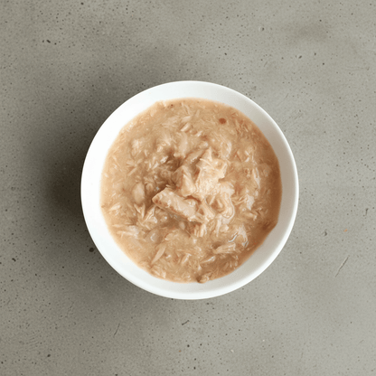 Wet cat food in white bowl, pale beige shredded meat with visible flakes