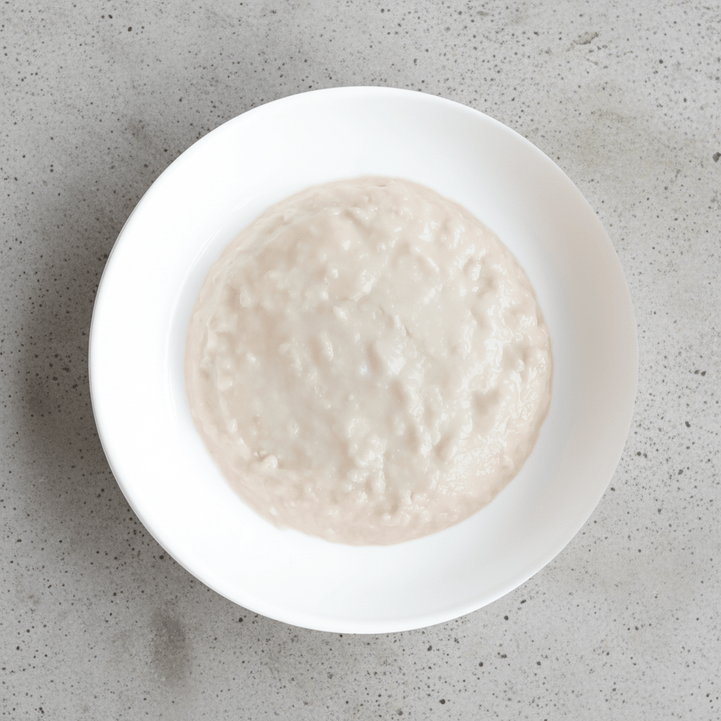 White ceramic bowl filled with pale kitten mousse cat food