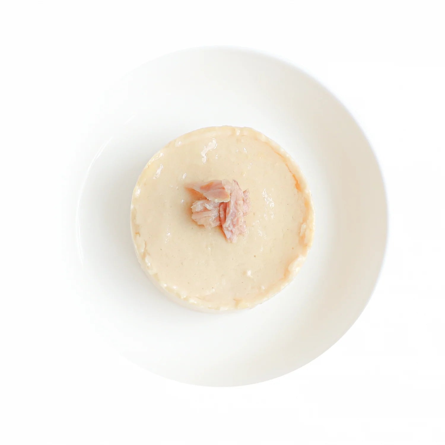 Cat mousse in a bowl, pale cream texture with small tuna pieces visible