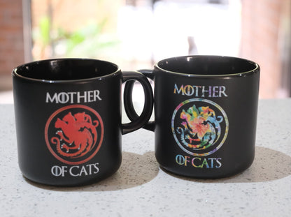 Two black Mother of Cats mugs, red cat seal on left and floral wreath on right