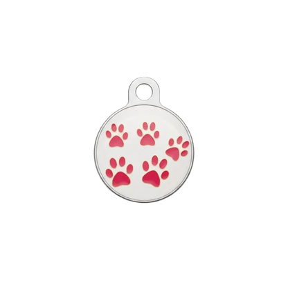 Round metal cat ID tag with scattered pink paw prints on light background.
