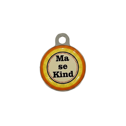 Round metal cat ID tag with 'Ma se Kind' text on orange-yellow striped background.