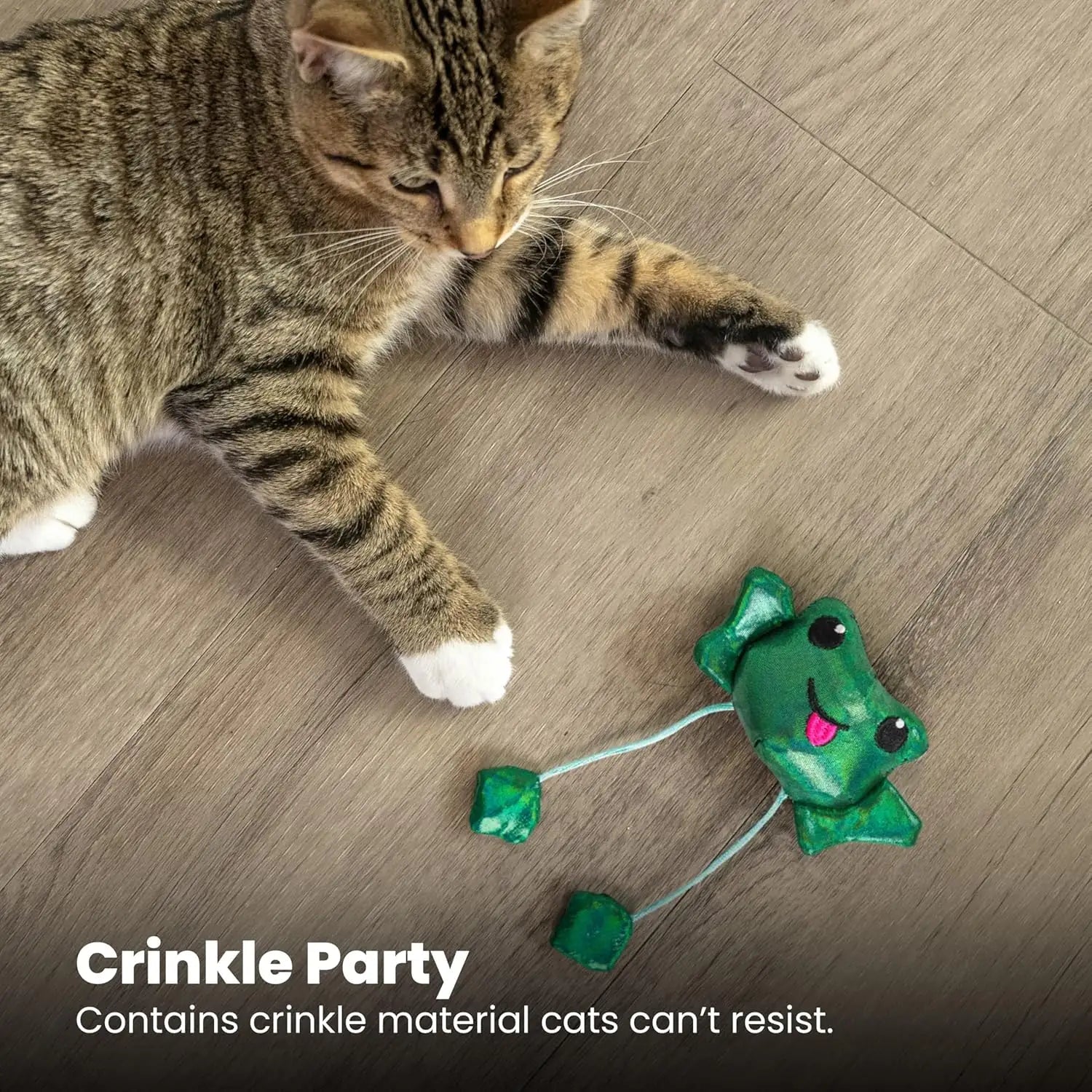 Green plush frog cat toy with dangling strings near a tabby cat, crinkle style