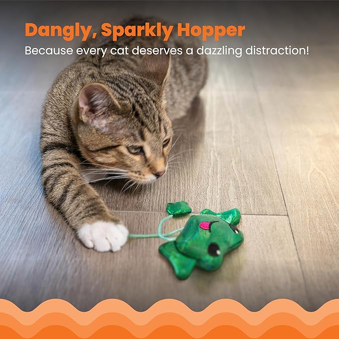 Green plush frog cat toy with dangling strings near a gray tabby cat