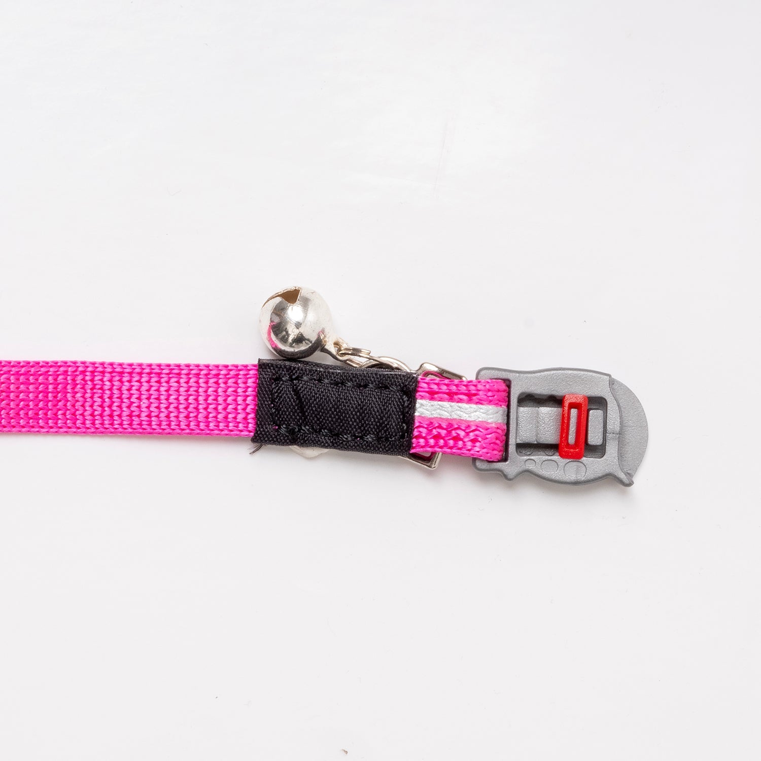 Pink-and-black breakaway cat collar closeup with silver bell and red buckle