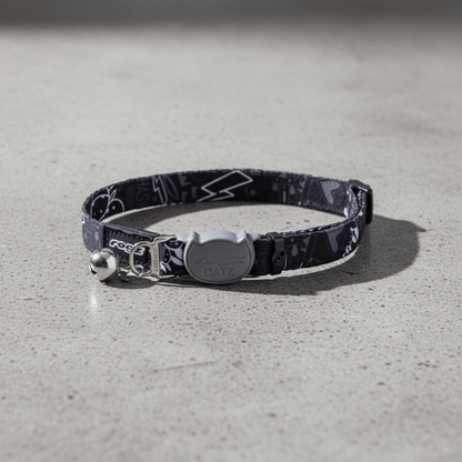 Black patterned safety collar with breakaway buckle and bell, laid flat