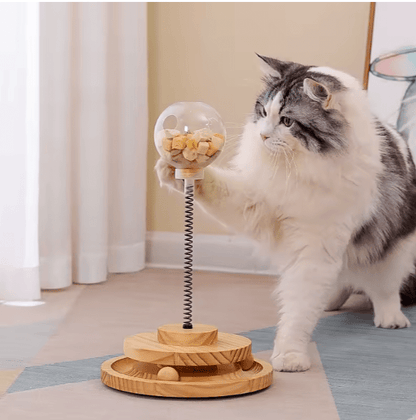 Interactive cat treat dispenser with clear top, spring, and wooden slow-feeder tray; cat